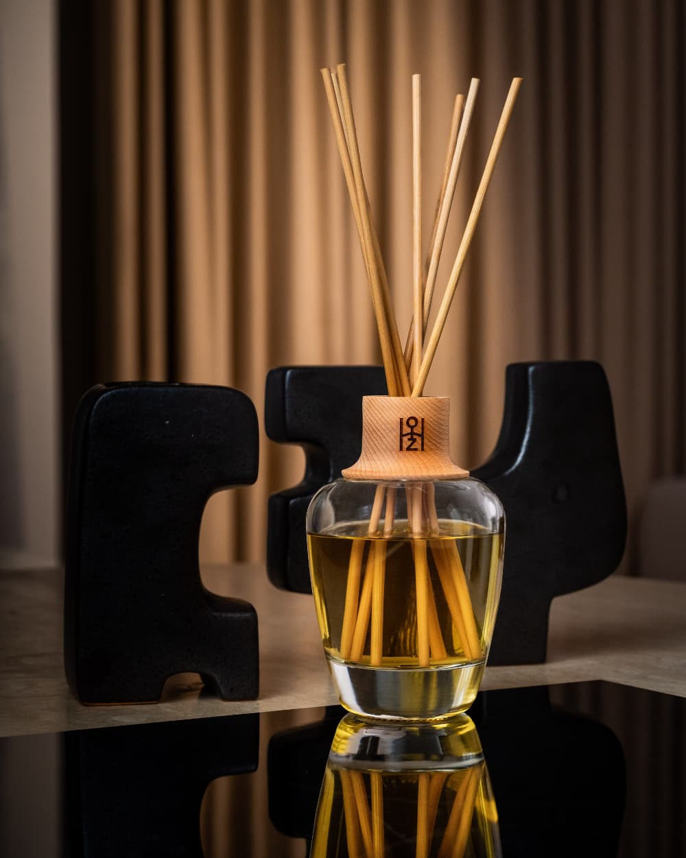 Diffuseur de parfum d’intérieur dans un décor chaud, devant une sculpture moderne